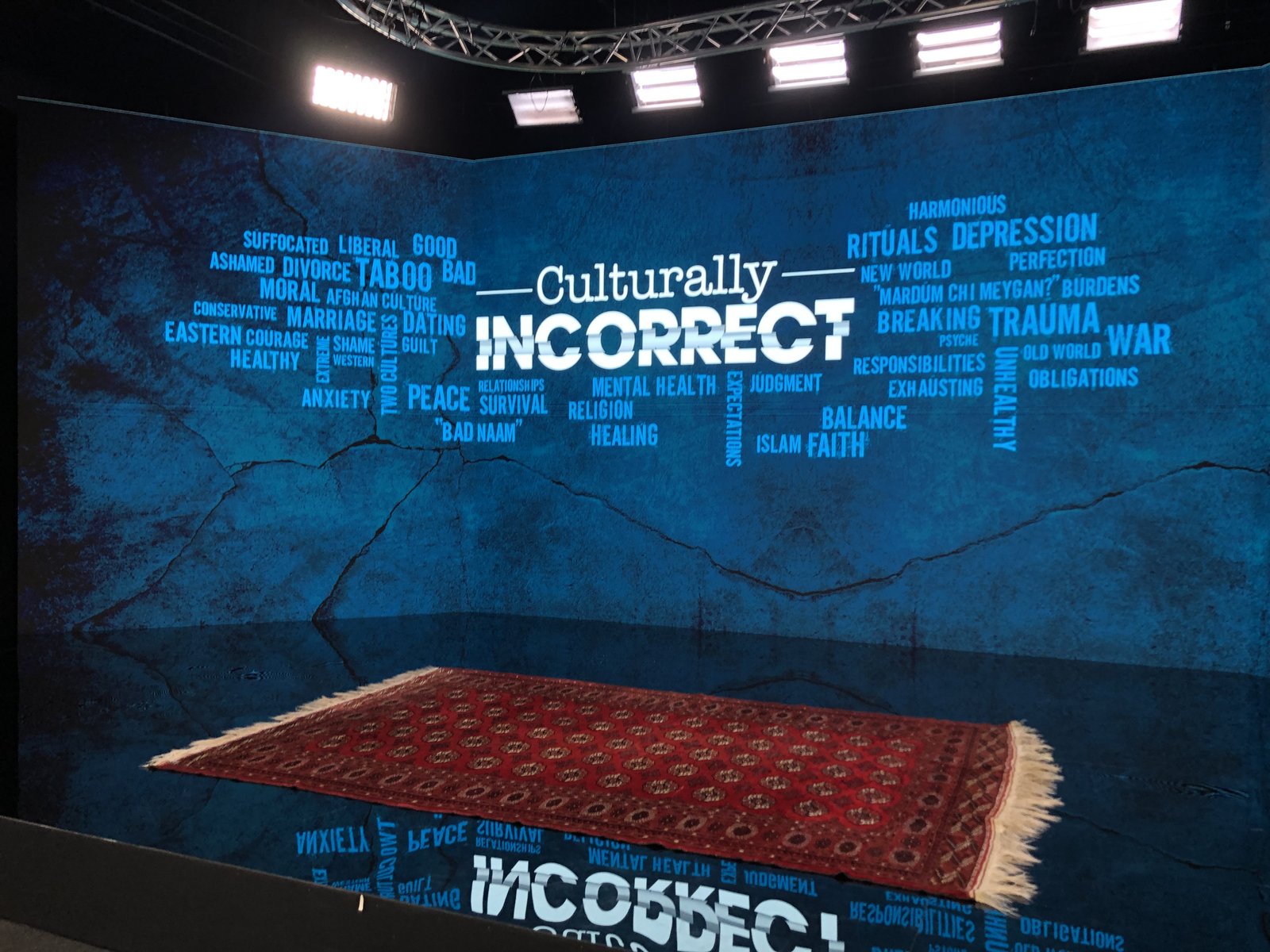 Culturally Incorrect studio set, with the show's word cloud of themes and a rug on the set floor